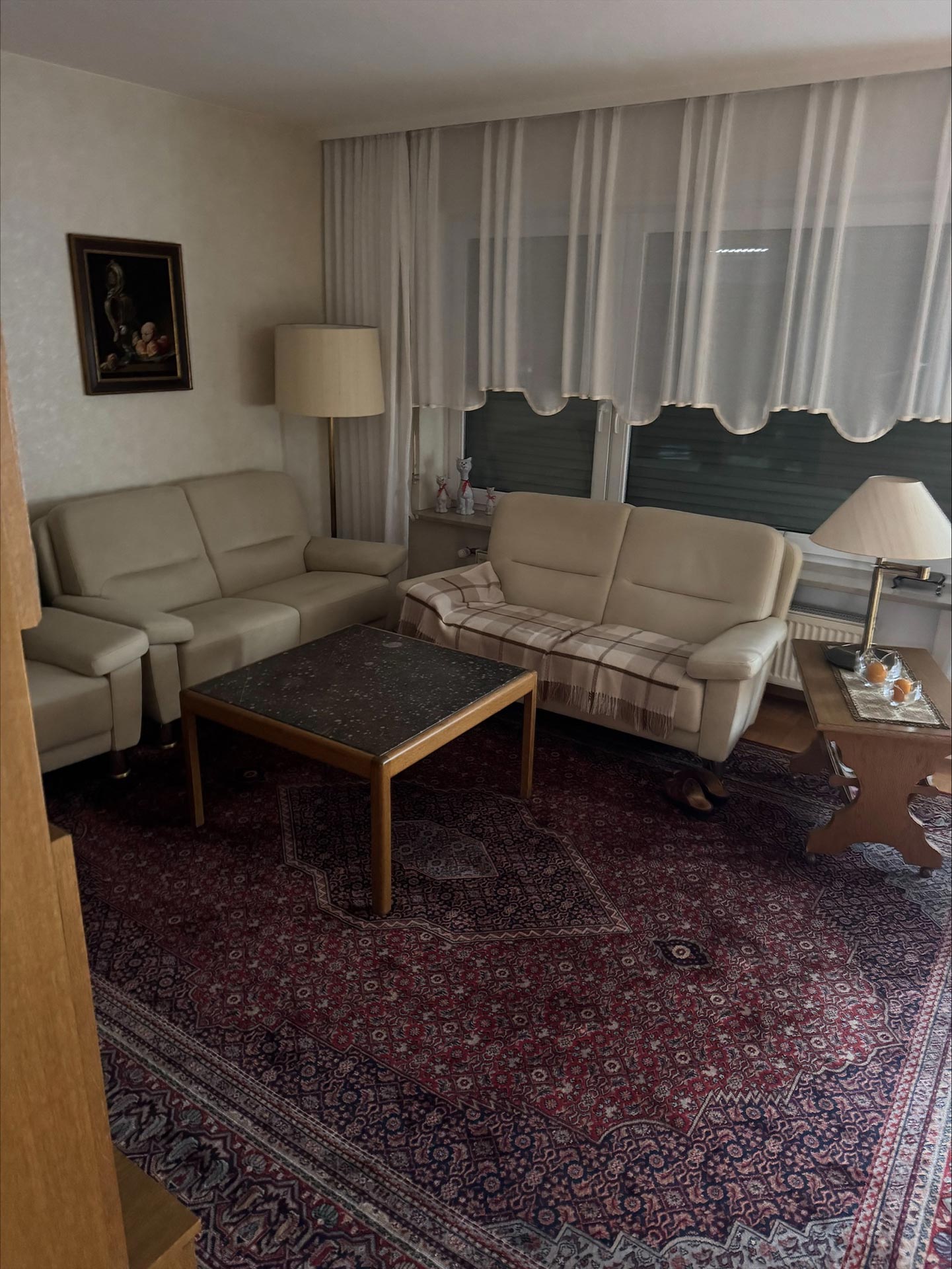 Helles Wohnzimmer mit zwei beigen Sofas, einem Teppich und einem dunklen Tisch